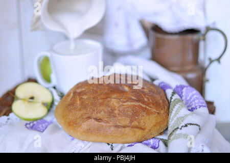 Homebaked pane. prodotti da forno. il latte in una brocca. vintage tovaglioli e tovaglia. tagliare apple Foto Stock