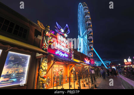 Seattle, Washington - 30 Giugno 2018 : Pier 57 a notte con le insegne al neon delle imprese del turismo e della grande ruota panoramica Ferris a Seattle, WA. Seattle l'acqua Foto Stock