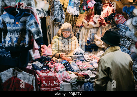Tallinn, Estonia - 21 dicembre 2017: Donna venditore vende vari colorato lavorate a maglia tradizionale europea vestiti caldi - cappelli Cappelli e guanti in inverno Foto Stock