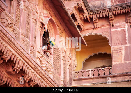 Guida indiana che indossa un turbante di guardare attraverso una finestra al Forte Mehrangarh, Jodhpur, India Foto Stock