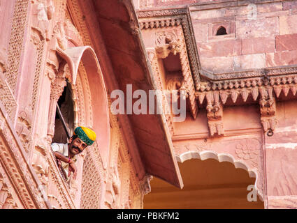 Guida indiana che indossa un turbante di guardare attraverso una finestra al Forte Mehrangarh, Jodhpur, India Foto Stock