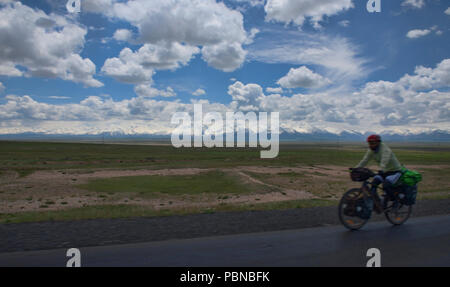 Ciclista in movimento nella parte anteriore del high Pamirs all inizio del Pamir Highway, Sary Tash, Kirghizistan Foto Stock