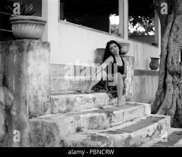 17 anni ragazza adolescente in una piscina esterna, ambientale portrait session. B&W medio formato pellicola. Foto Stock