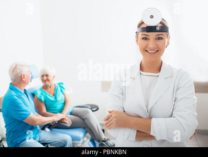 Sorridendo Il medico ORL in piedi prima di pazienti anziani in ufficio medico Foto Stock