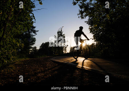 Immagine del ciclista che indossa il casco equitazione intorno città in serata Foto Stock