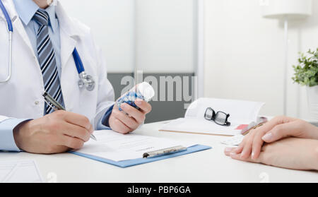 Il medico e il paziente in ufficio. Medico prescrive la ricetta. Tenendo una bottiglia di pillole. Foto Stock