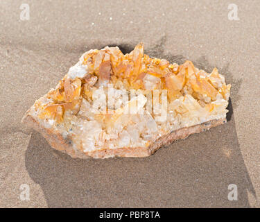 Golden guaritore Cluster campione di quarzo da Arkansas sulla sabbia bagnata sulla spiaggia di sunrise. Foto Stock