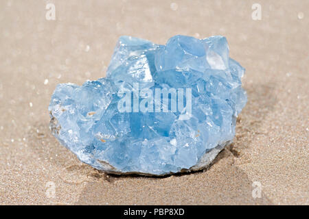 Blue Celestite cluster dal Madagascar giacente sulla sabbia bagnata sulla spiaggia di sunrise. Foto Stock