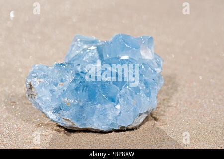 Blue Celestite cluster dal Madagascar giacente sulla sabbia bagnata sulla spiaggia di sunrise. Foto Stock