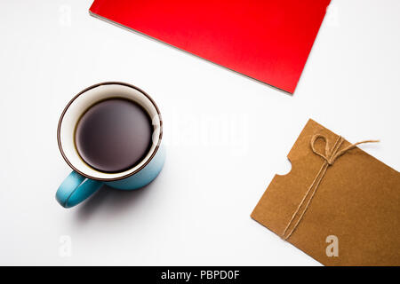 Una tazza di tè, red book e lettera su sfondo bianco Foto Stock