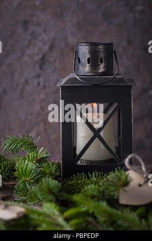 Composizione di natale con candela lanterna e abeti bianchi su sfondo scuro Foto Stock