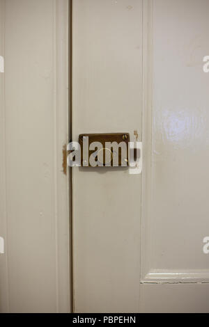 Close up detail of a brass door lock on a white painted door. Foto Stock