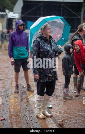 Cumbria, Regno Unito. 29 luglio 2018 i frequentatori del festival sfidando la pioggia indossando poncho e ombrelloni mentre vi godete la musica a Kendal chiamando, Penrith. © Jason Richardson / Alamy Live News Foto Stock