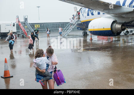 I turisti che arrivano all'aeroporto di Leeds Bradford dalla Spagna sotto la pioggia torrenziale. REGNO UNITO Foto Stock