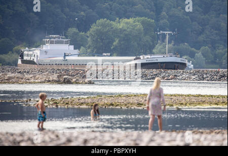 Bingen, Germania. 29 Luglio, 2018. Una donna e due bambini bedan presso la riva del Reno tra Bingen e Rüdesheim, mentre nella parte superiore di una nave terrestre si sposta fino al fiume, che è molto stretto a causa del basso livello dell'acqua. Credito: Frank Rumpenhorst/dpa/Alamy Live News Foto Stock