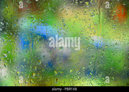 Chesil Beach. Il 29 luglio 2018. Regno Unito: Meteo le gocce di pioggia scorrere verso il basso un vetro che si affacciava su un colorato giardino sulla isola di Portland Credit: stuart fretwell/Alamy Live News Foto Stock