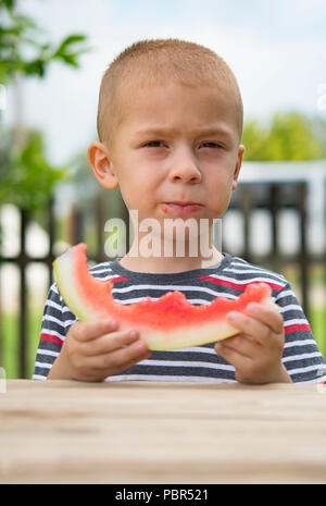 Bambino felice mangiando anguria in giardino Foto Stock