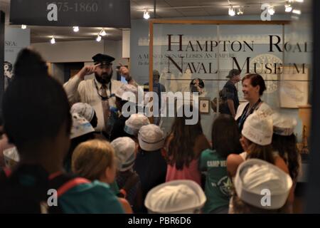 Giuseppe Miechle (in piedi con replica hat) museo educatore, fornisce alcune indicazioni per energico campeggiatori che hanno visitato l'Hampton Roads Museo Navale. Dietro la scrivania è Laura Orr, il museo educatore Direttore. (US Navy Foto di civili di Public Affairs Officer Max Lonzanida/rilasciato) Foto Stock