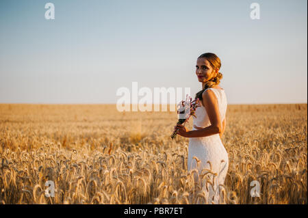 Sposa tiro con un mazzo di fiori in un campo Foto Stock