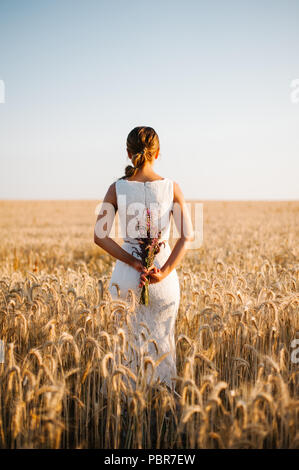 Sposa tiro con un mazzo di fiori in un campo Foto Stock