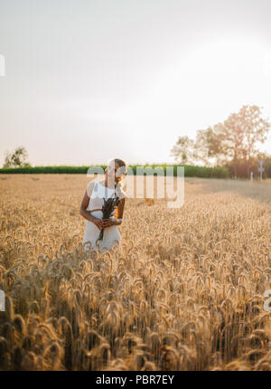 Sposa tiro con un mazzo di fiori in un campo Foto Stock