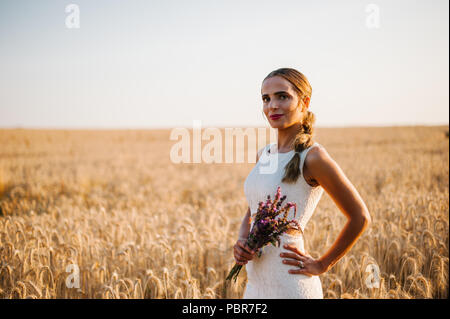 Sposa tiro con un mazzo di fiori in un campo Foto Stock