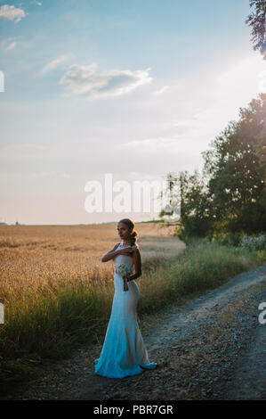 Sposa tiro con un mazzo di fiori in un campo Foto Stock