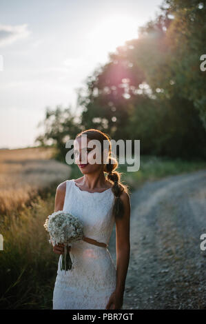 Sposa tiro con un mazzo di fiori in un campo Foto Stock