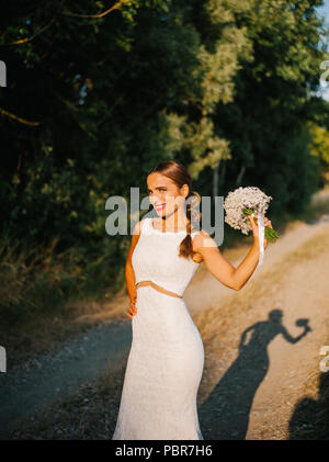 Sposa tiro con un mazzo di fiori in un campo Foto Stock