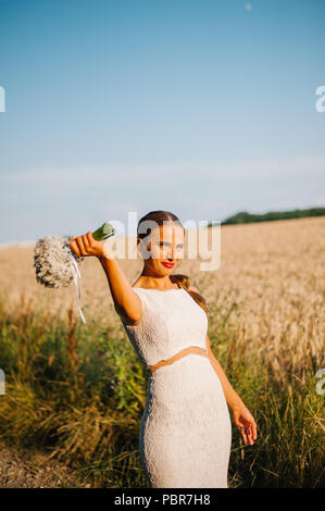 Sposa tiro con un mazzo di fiori in un campo Foto Stock