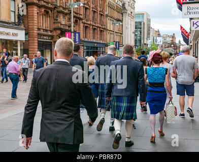 Donna vestita per nozze con uomini in kilts camminando su occupato Buchanan Street, Glasgow, Scotland, Regno Unito Foto Stock