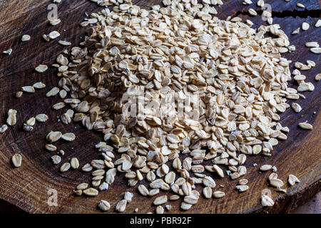 Farina di avena fiocchi d'avena heap di grana ruvida sul tagliere di legno dal lato Foto Stock