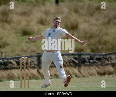 Un bowler veloce in azione in una partita di cricket tra Birch Vale e Thornsett secondo team e Stalybridge San Paolo seconda squadra. Foto Stock