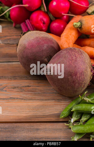 Barbabietole, piselli, carote e ravanelli su un tavolo di legno. Close up. Maturi freschi ortaggi. Foto Stock