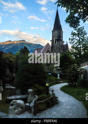 Antica pietra Schlosskirche Cattolica (Castello) chiesa sorge su un ornamentali giardino giapponese con un bellissimo sfondo cielo, Interlaken, Svizzera. Foto Stock
