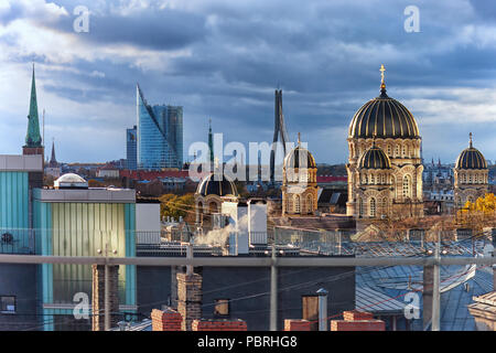 Urban vista sui tetti della città vecchia di Riga, con i camini e le guglie delle cattedrali e delle chiese nella splendida luce della sera Foto Stock