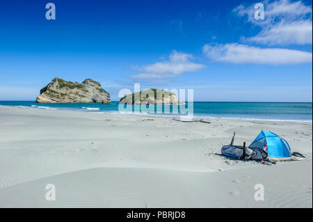 Tenda da campeggio sulla spiaggia Wharariki con arcata di isole in background, Isola del Sud, Nuova Zelanda Foto Stock