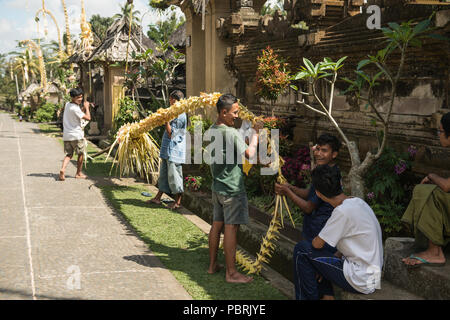 Gli abitanti di un villaggio di Bali dare il tocco finale a una tradizionale penjor decorazione di strada prima della formatura di essa durante il festival indù di Galungan. Foto Stock