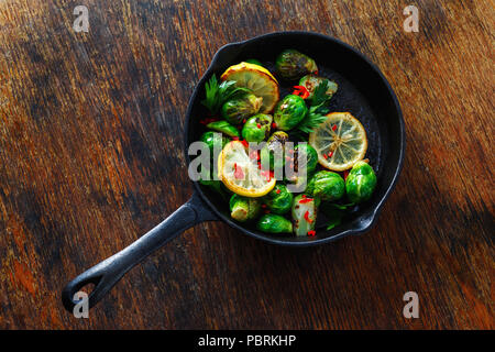 Broccoli fritti serviti in ghisa padella sul tavolo di legno vista superiore sano cibo vegetariano Foto Stock