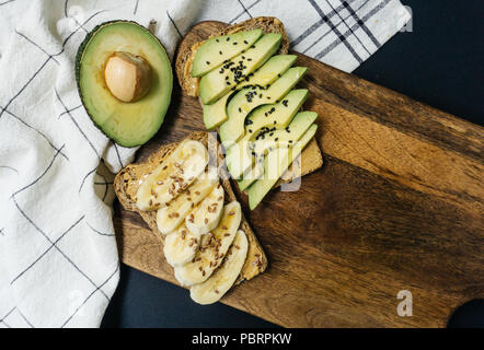 Toast con avocado, di sesamo e burro di arachidi sul grano intero pane e toast con banana e lino su tutto il pane di grano Foto Stock