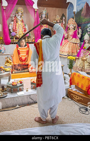 Un adolescente onde pandit una spada mentre conduce uno speciale servizio della gioventù a Milano Mandir in Sud Ozone Park, Queens, a New York City. Foto Stock