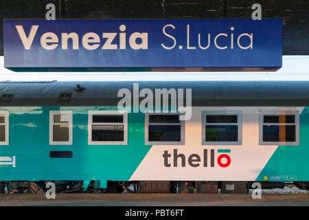 Thello per una notte di treno passeggeri tra Parigi e Venezia in Venezia S Lucia, Venezia, Veneto, Italia al tramonto . Segno di stazione, logo del treno Foto Stock