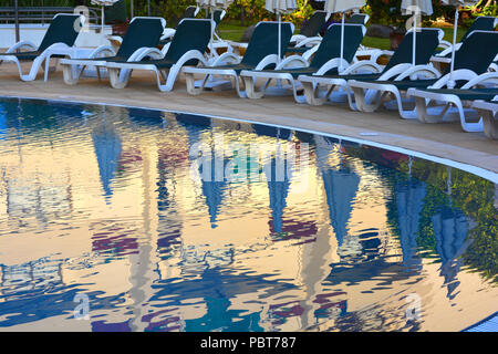 Piscina presso un hotel resort. Vista serale della piscina con lettini per prendere il sole si riflette nell'acqua ancora