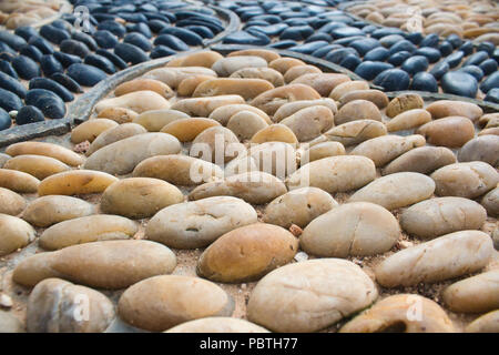 Giallo lucido bianco pietre di fiume inset in una configurazione a mosaico su una passerella Foto Stock