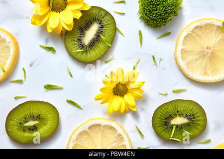 Modello di fiori di colore da giallo, verde fiori, fette di kiwi e limone. Close-up di sfondo a molla da ingredienti biologici. Foto Stock