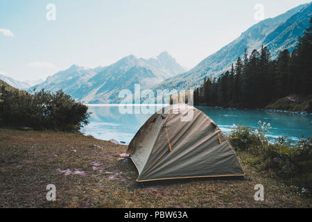 Tenda da campeggio in campeggio a parco nazionale. I turisti accampati nei boschi sulla riva del lago sulla collina. Vista della tenda sul prato in foresta. Foto Stock