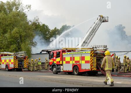 Glasgow, Regno Unito. Il 30 luglio, 2018. Glasgow, Scotland, Regno Unito. Un incendio di grandi dimensioni forza la chiusura di Crookston Rd di Glasgow come pompieri la linea street e vigili del fuoco utilizzare apparecchi di respirazione e di alta raggiungere piattaforme per affrontare il blaze. Credito: Carr Douglas/Alamy Live News Foto Stock