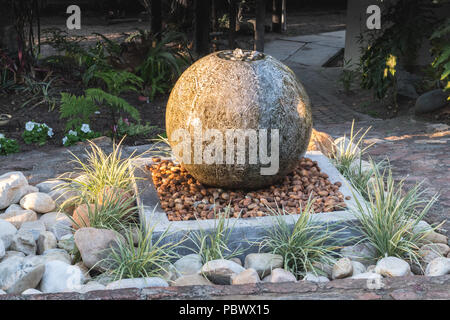 Fontana nel giardino al tramonto Foto Stock