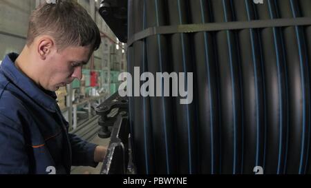 RUSSIA, ANGARSK - Giugno 8, 2018: bobina bobina di filettatura tubo. Fabbricazione di plastica tubazioni acqua fabbrica. Processo per la fabbricazione di tubi di plastica sulla macchina utensile con l uso dell acqua e la pressione dell'aria. Foto Stock