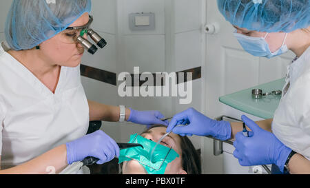 Donna al dentista clinica riceve il trattamento dentale per riempire una cavità di un dente. Restauro dentale e materiale composito la polimerizzazione con luce UV e laser. Foto Stock